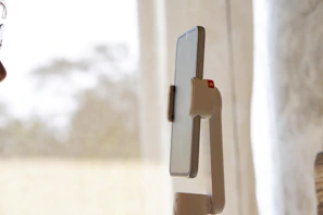 A tall floor stand with a flexible arm supporting a phone in a cozy living room setting.