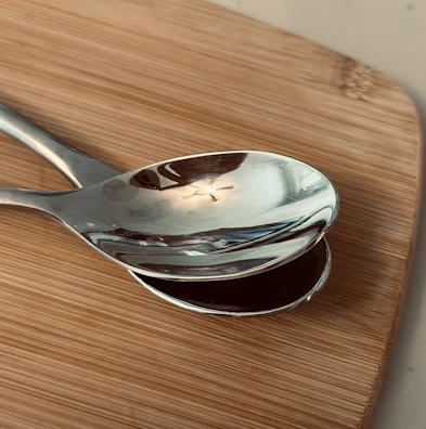 Close-up of shiny stainless steel measuring spoons resting on a recipe book.