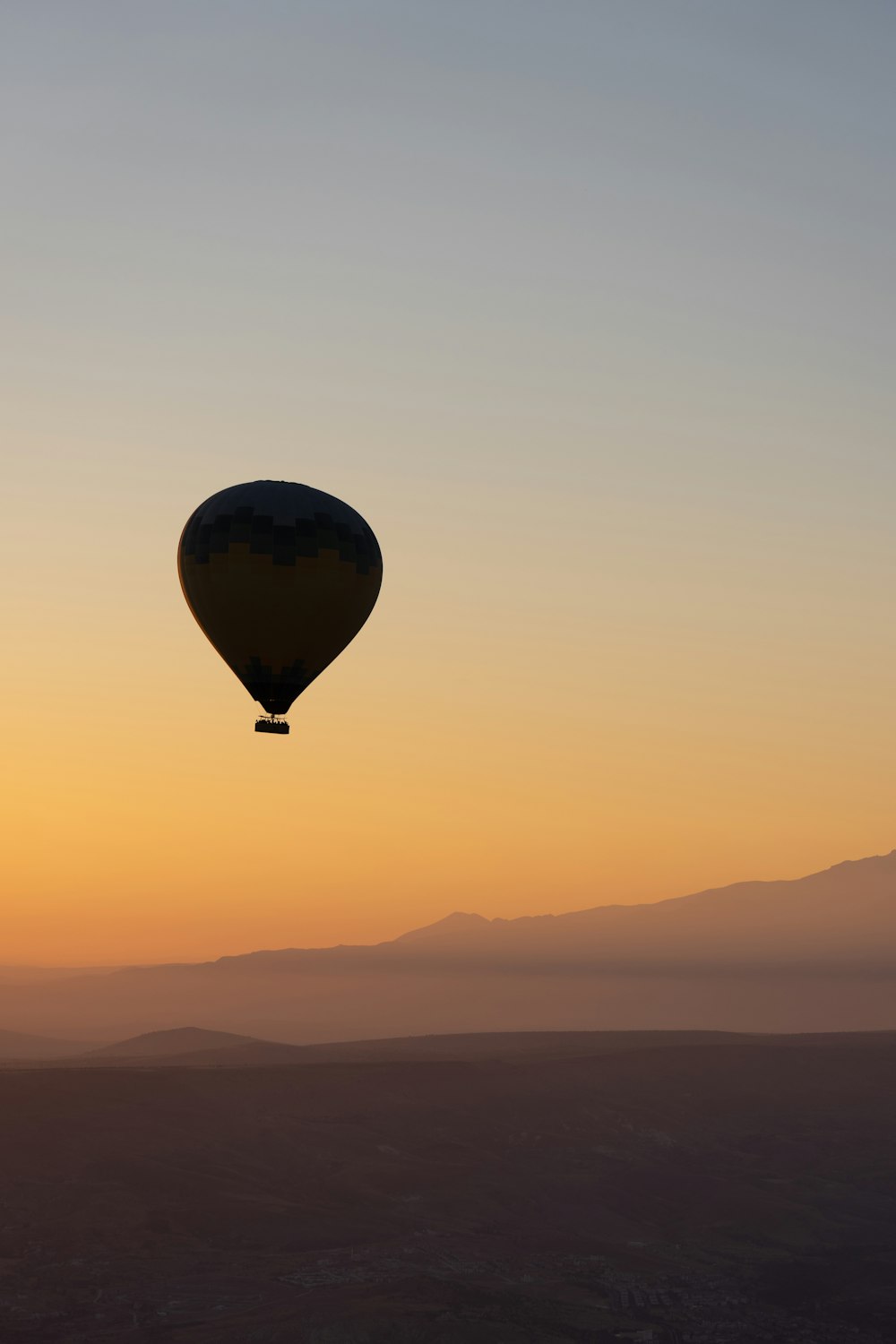 a hot air balloon flying in the sky at sunset