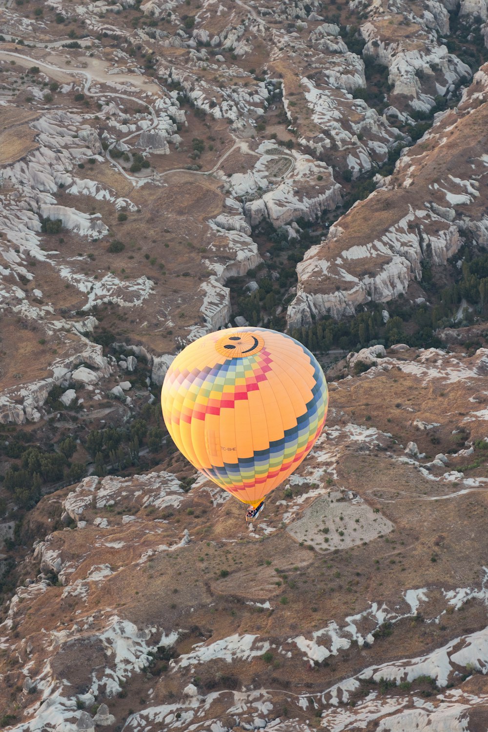 a hot air balloon flying over a rocky hillside