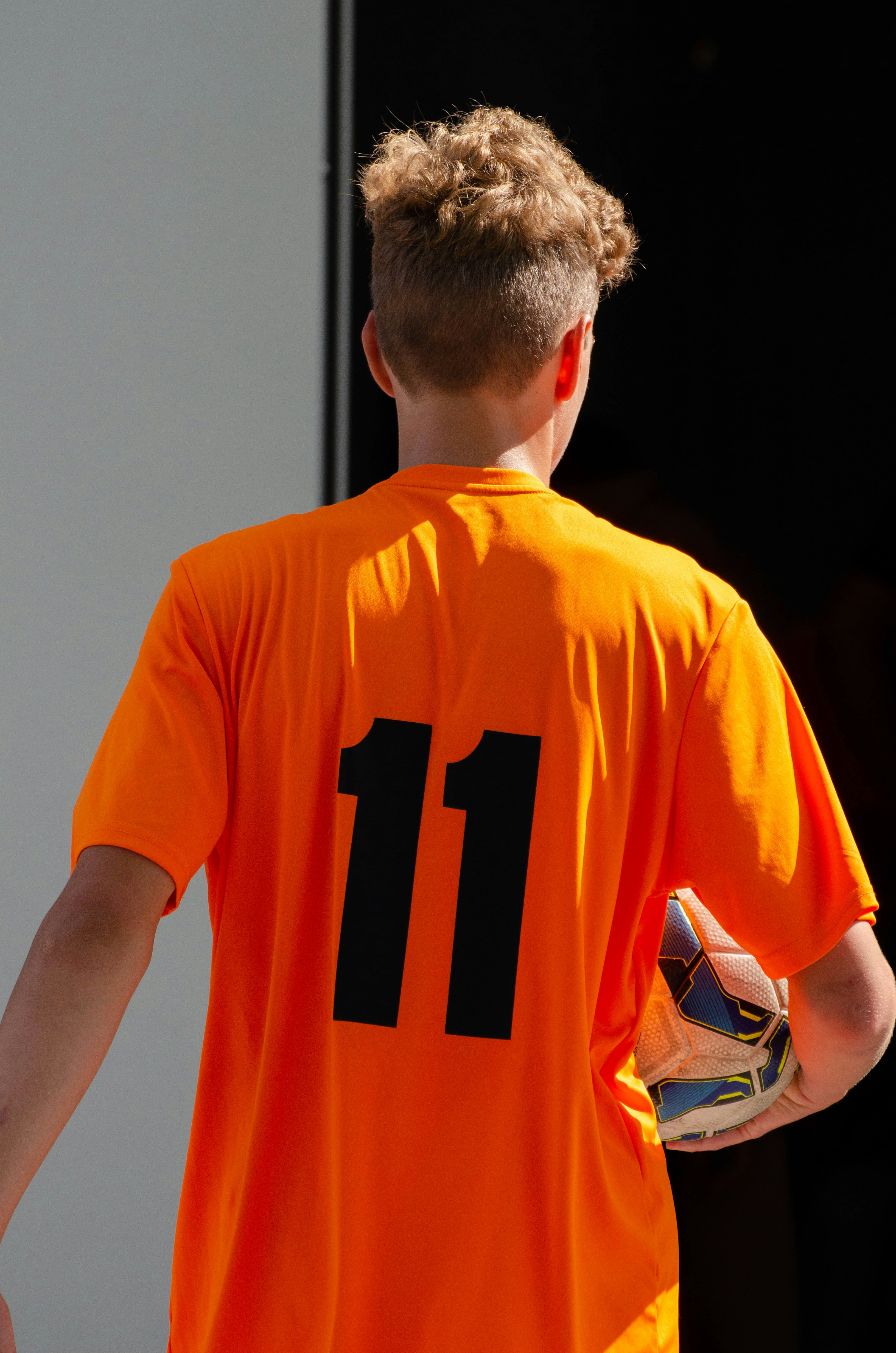 a young boy wearing an orange soccer jersey