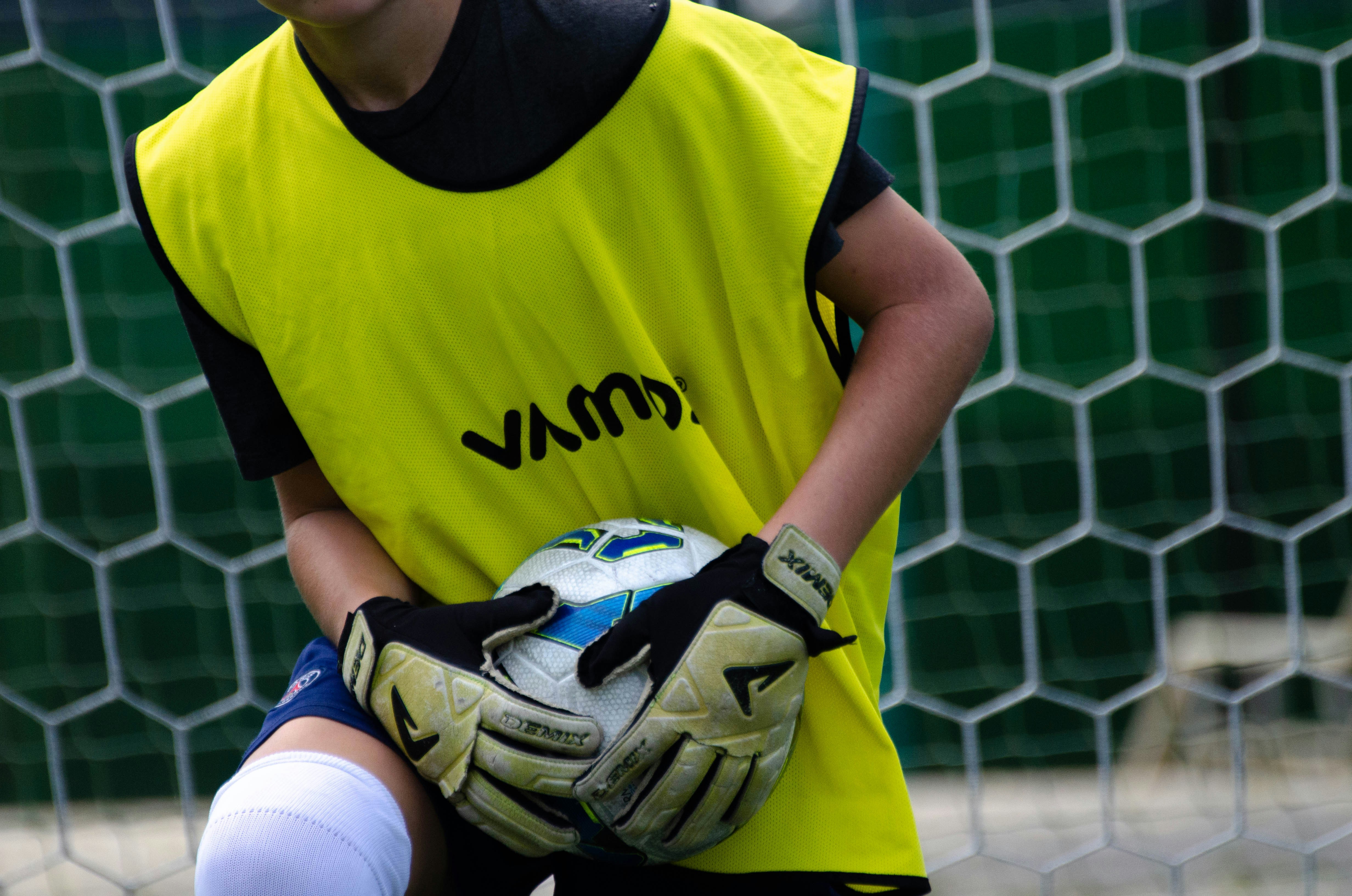 a young man holding a soccer ball in front of a net
