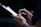 A close-up of a person holding a pen and a clipboard, seemingly taking notes or writing something. The setting appears to be dimly lit with focus on the hands and the writing action.