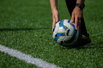 a soccer ball being held by a person on a field