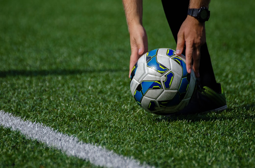 a soccer ball being held by a person on a field