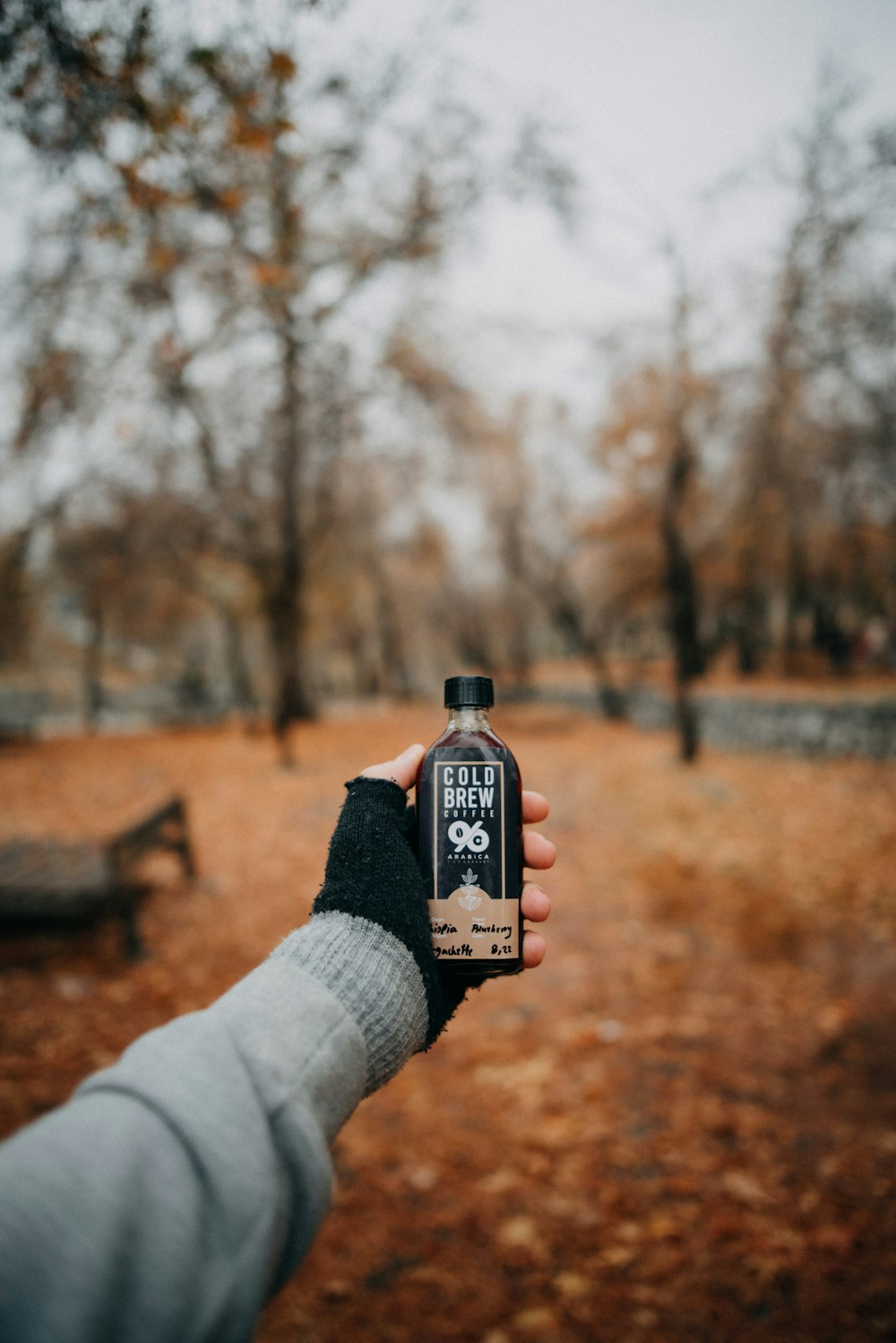 a person holding a bottle of beer in a park