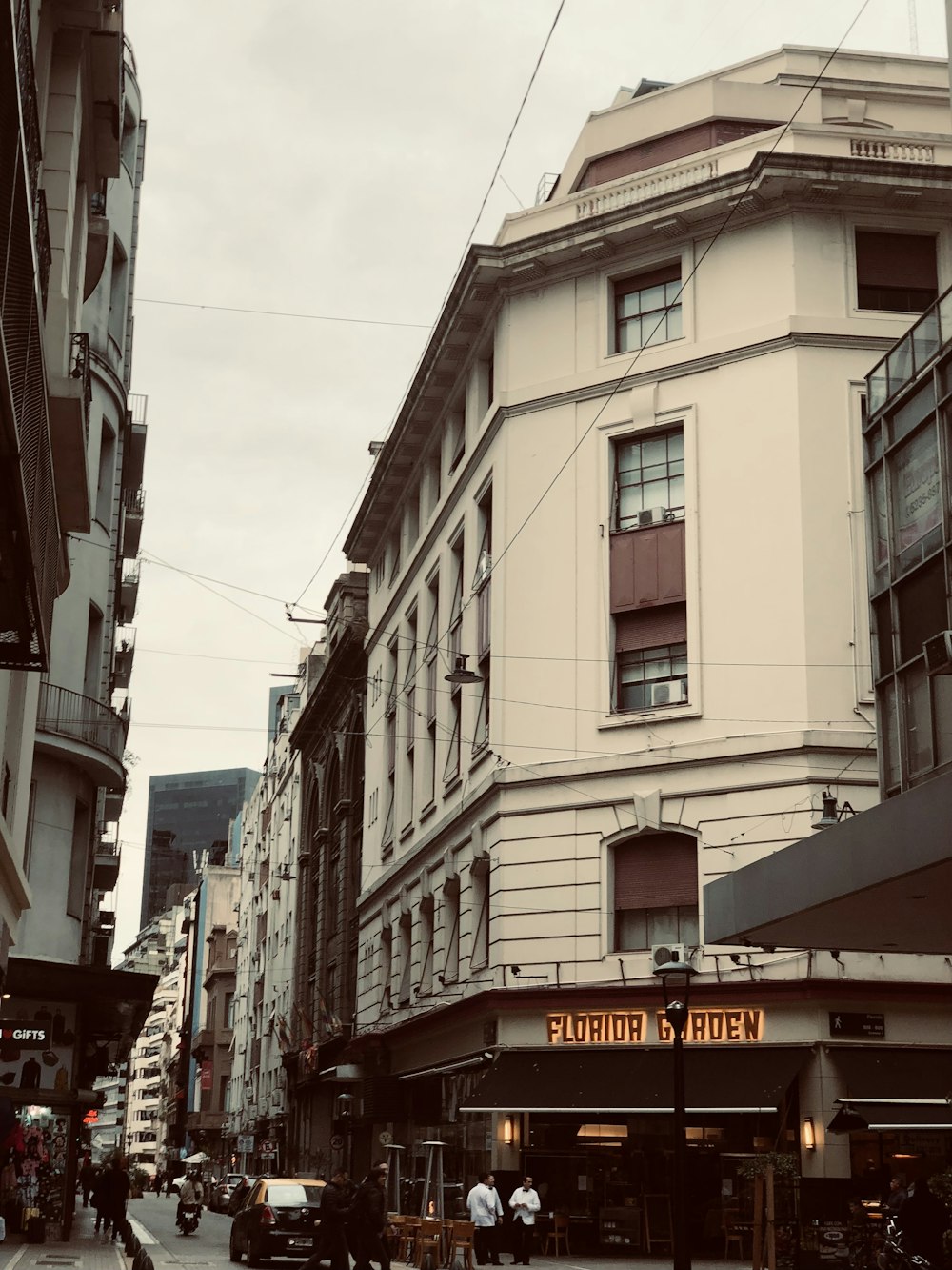 a group of people walking down a street next to tall buildings