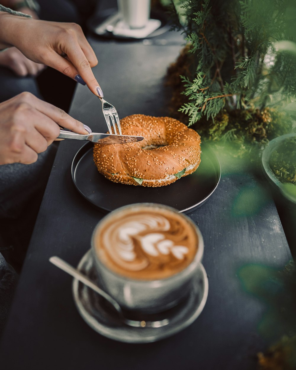 a person cutting into a bagel with a fork