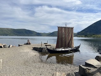 a boat sitting on the shore of a lake