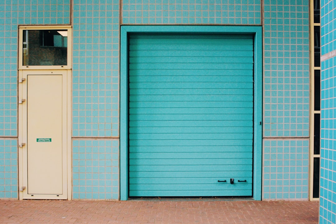 a blue building with a white door and a brick sidewalk, Blue wall of tiles with cream hints