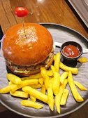 Burger placed on a wooden platter accompanied by fries and a dipping sauce.