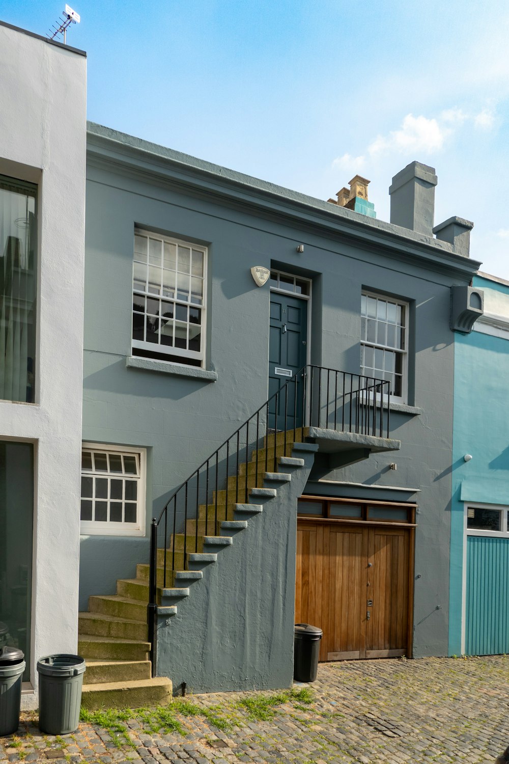 a grey house with a wooden door and stairs