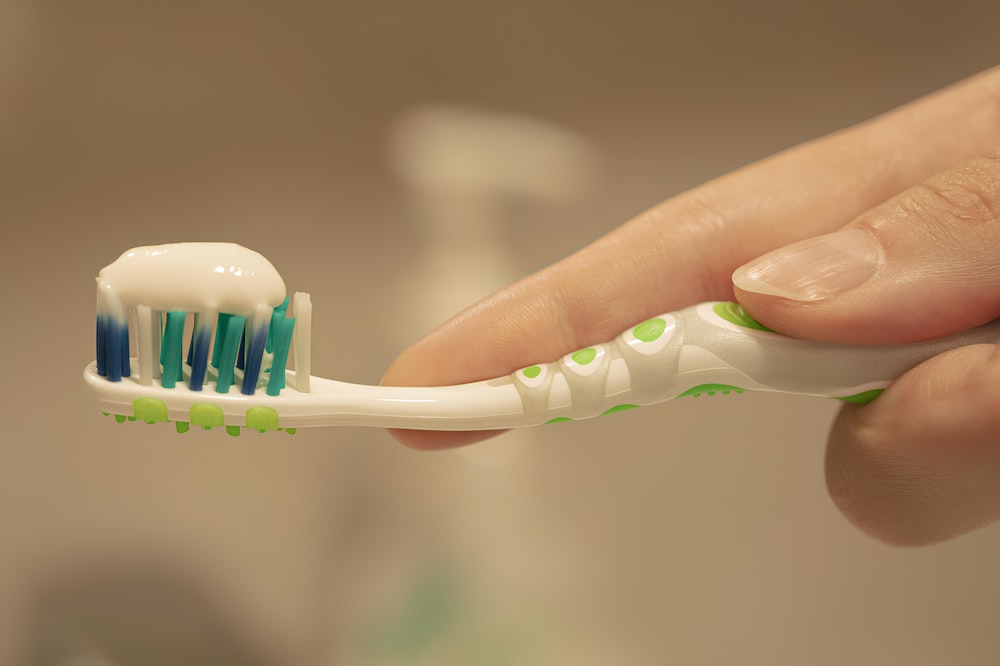 una persona tiene in mano uno spazzolino da denti con il dentifricio su di esso