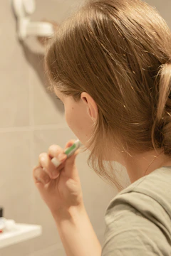 An individual practicing self-care by brushing their hair in a modern bathroom.