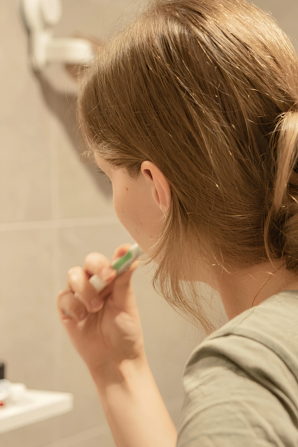 İllüstratif görsel: a woman brushing her teeth in a bathroom