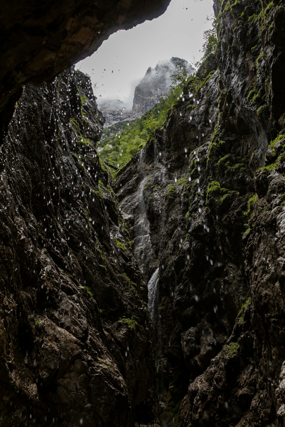 a cave entrance with a stream of water coming out of it