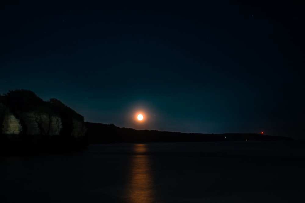 a full moon is seen over a body of water