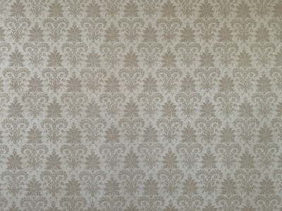 A classic damask wallpaper pattern featuring intricate floral motifs with a symmetrical design. The pattern is repetitive and evenly distributed across the surface, conveying a sense of elegance and tradition.