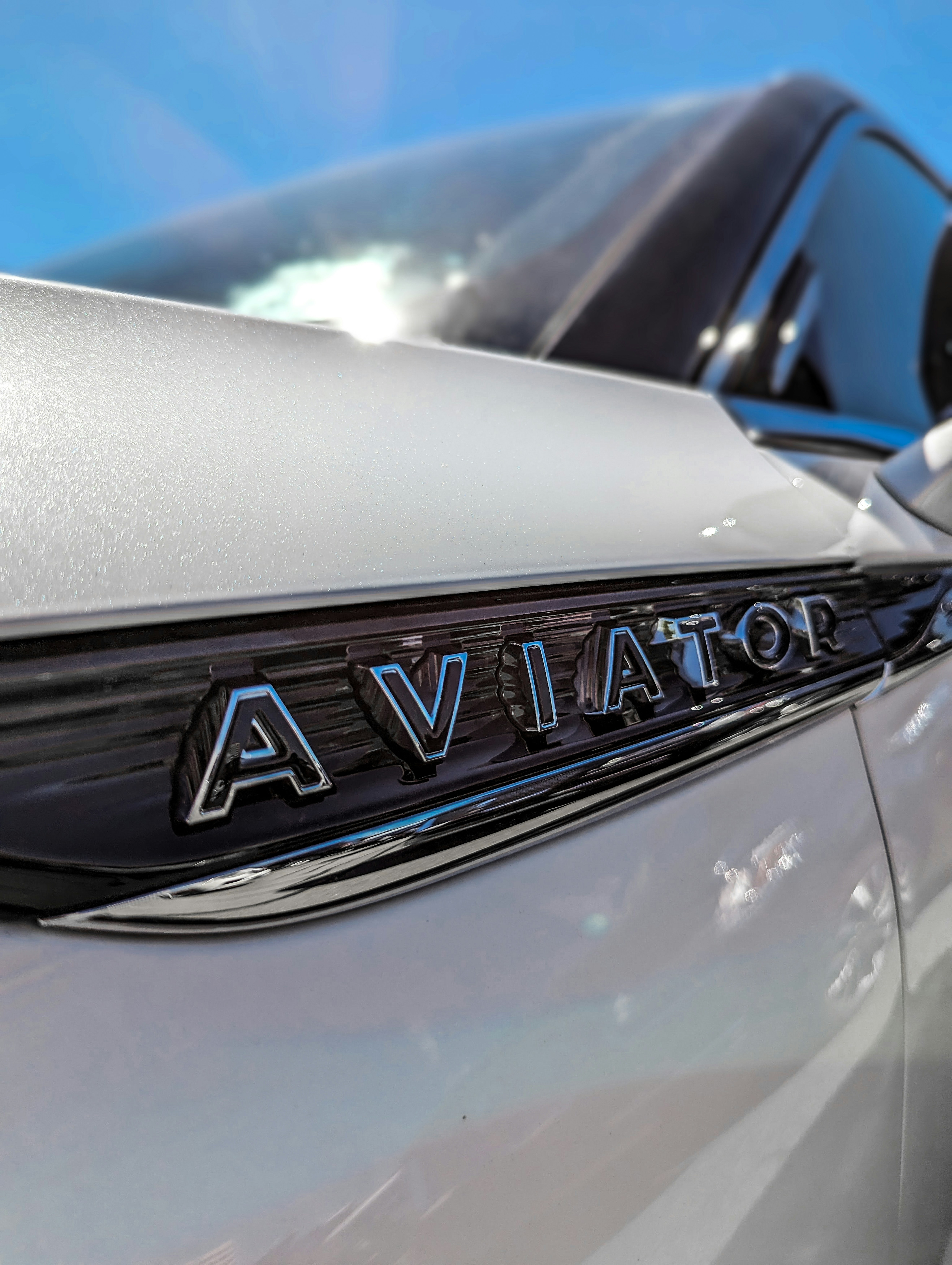 a close up of a silver car with a blue sky in the background