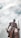 A stately bronze statue of a warrior stands against a backdrop of cloudy skies. The figure is adorned in traditional attire and holds a weapon in each hand, exuding strength and determination.
