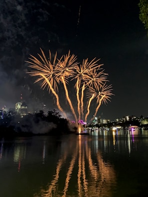 Golden fireworks cascading like shimmering rain over a cityscape at night.