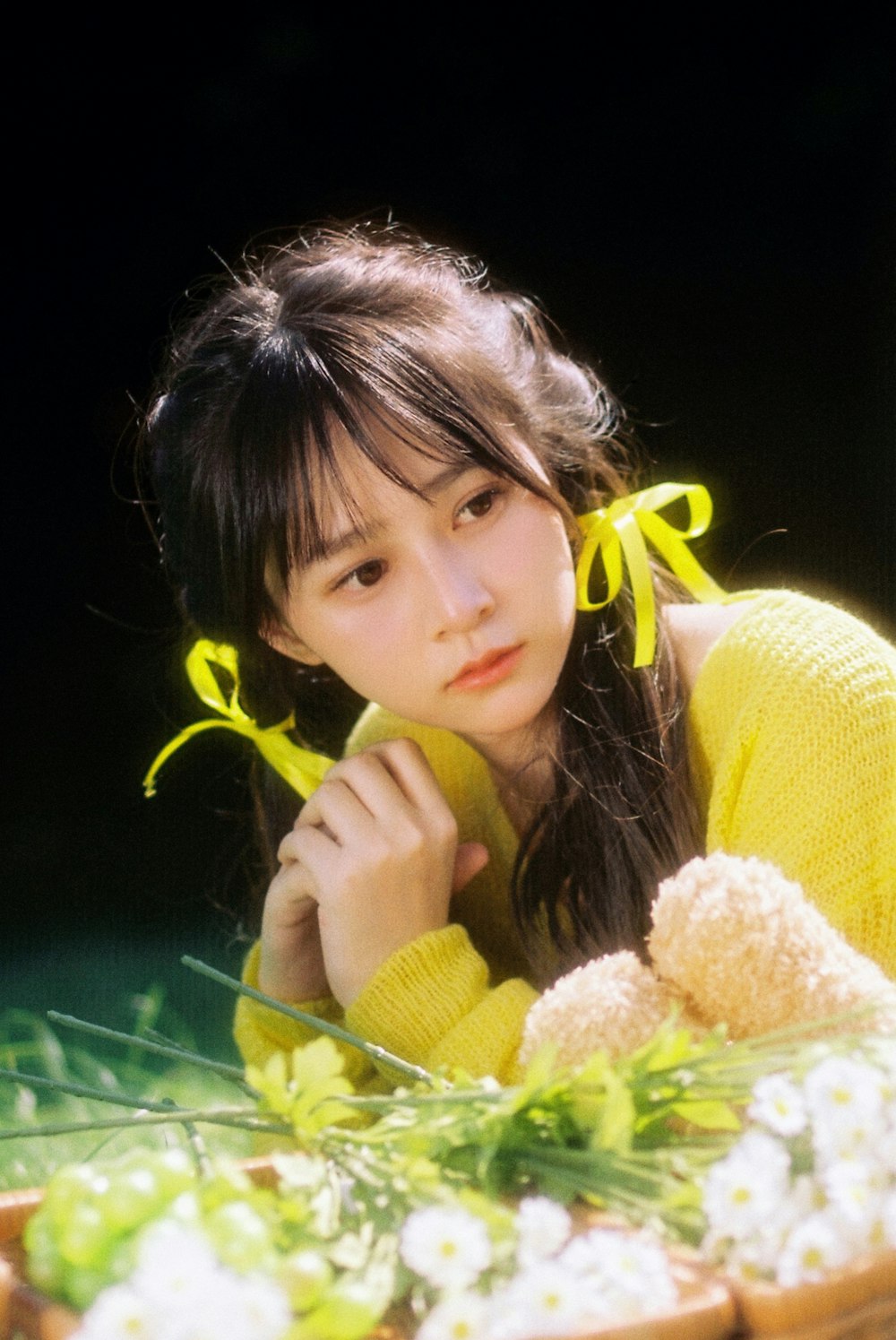 a woman in a yellow sweater sitting next to a basket of flowers