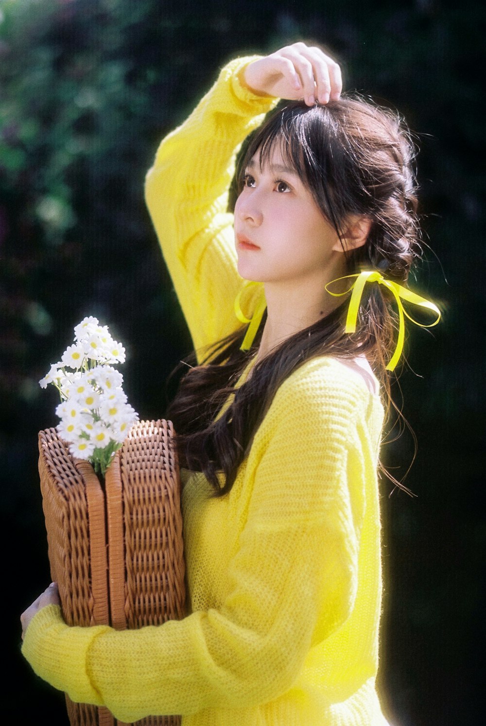 a woman in a yellow sweater holding a basket of flowers