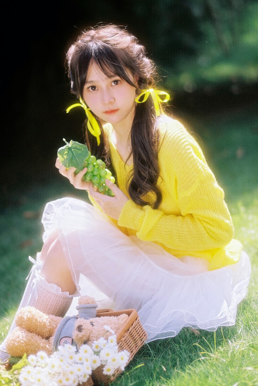 a girl in a yellow sweater and white skirt holding a green leaf