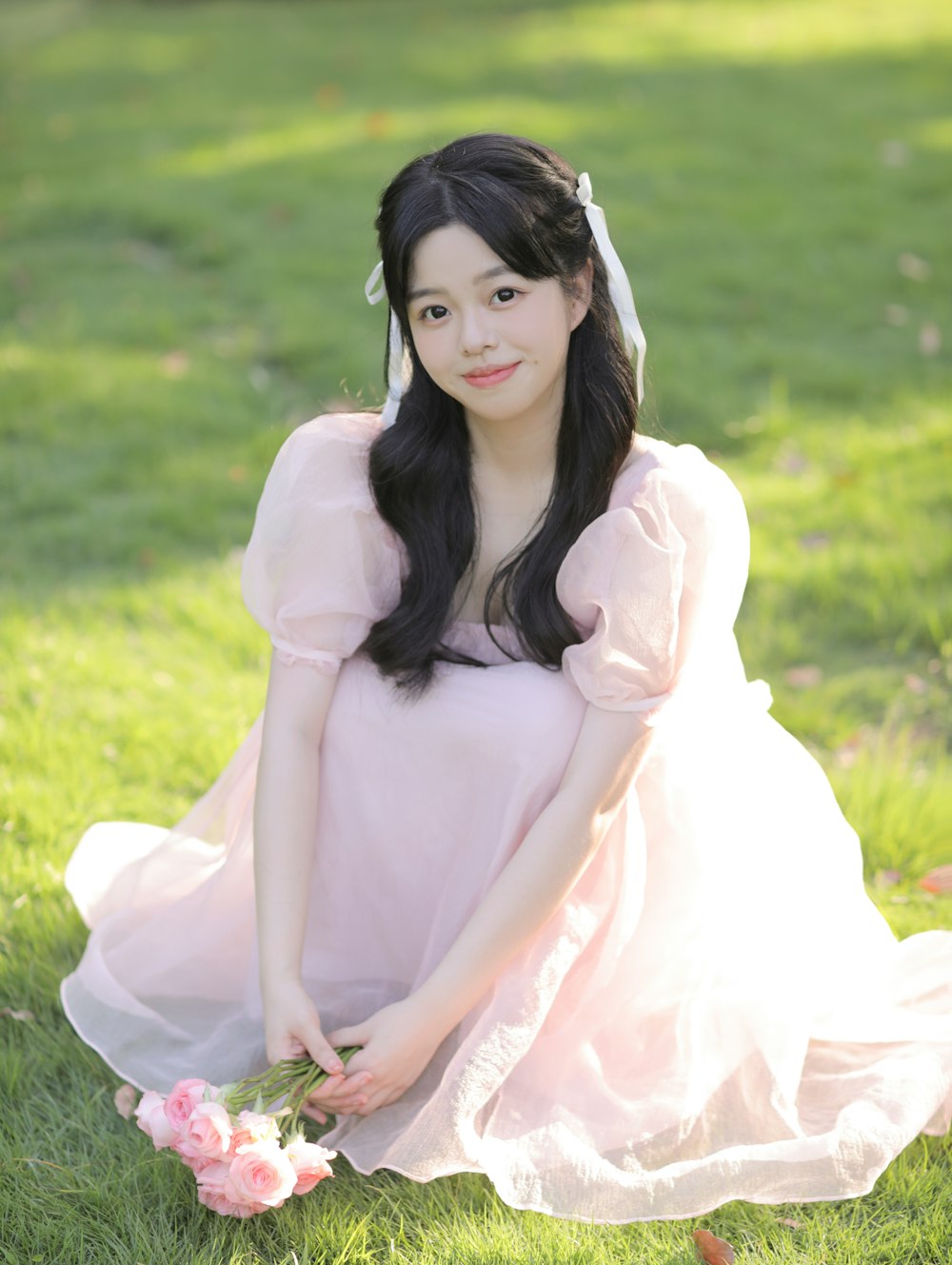 a woman in a pink dress sitting in the grass