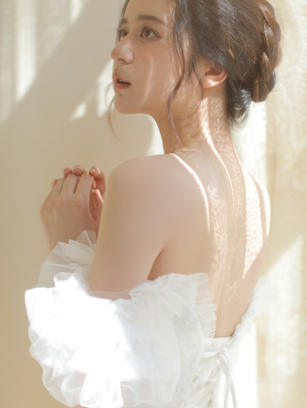 a woman in a white dress standing in front of a window