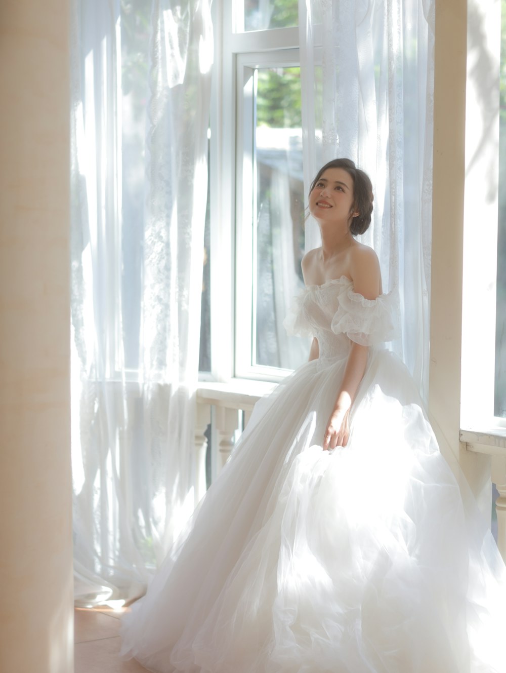 Una mujer con un vestido de novia parada frente a una ventana