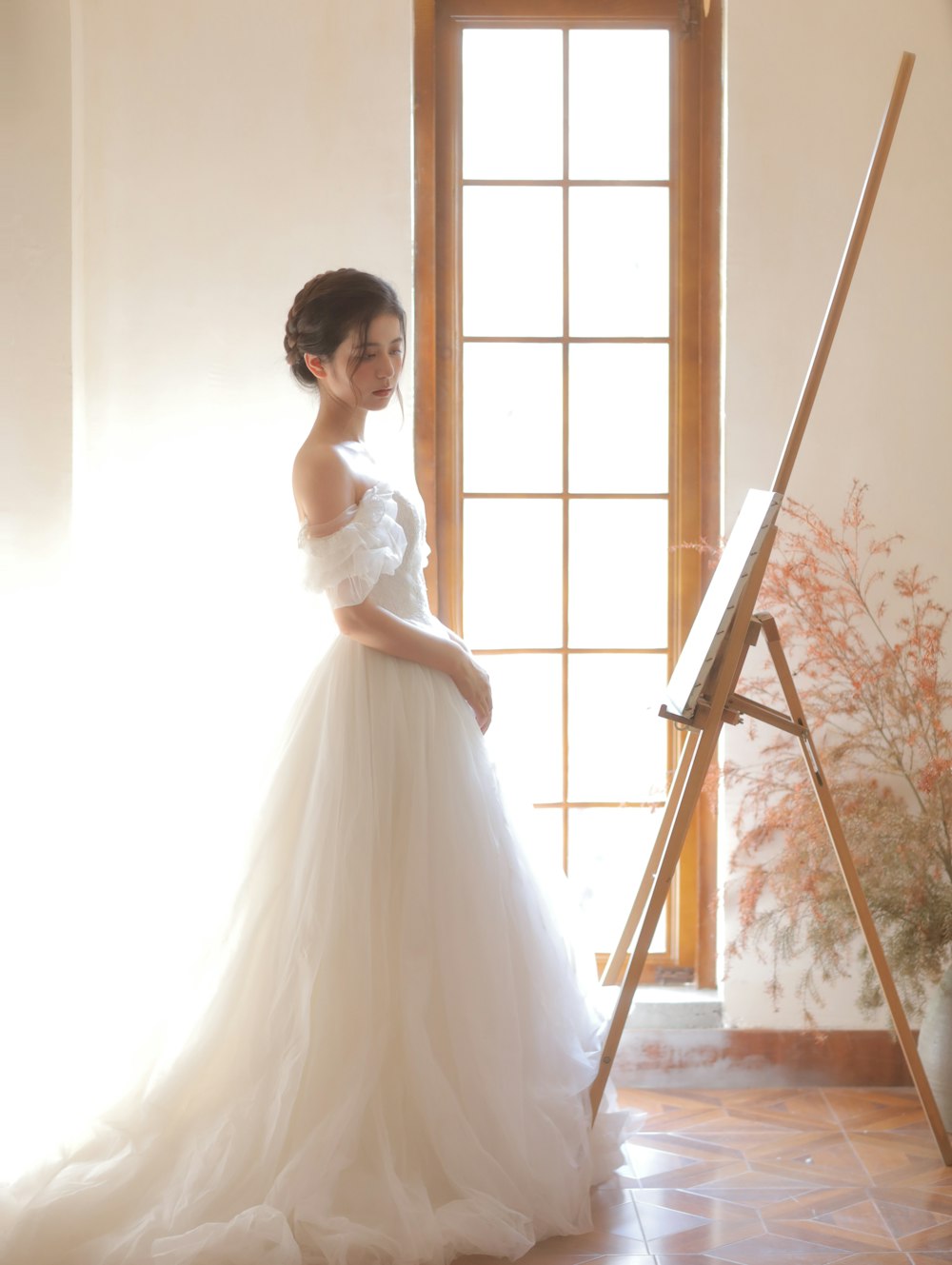 a woman in a wedding dress standing in front of a easel
