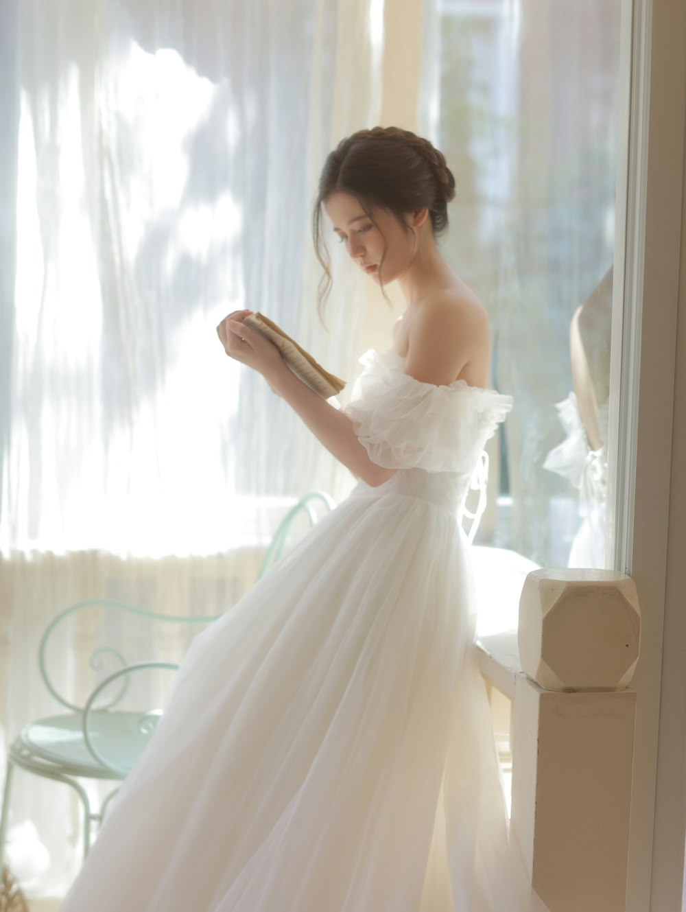 a woman in a white dress looking at a book