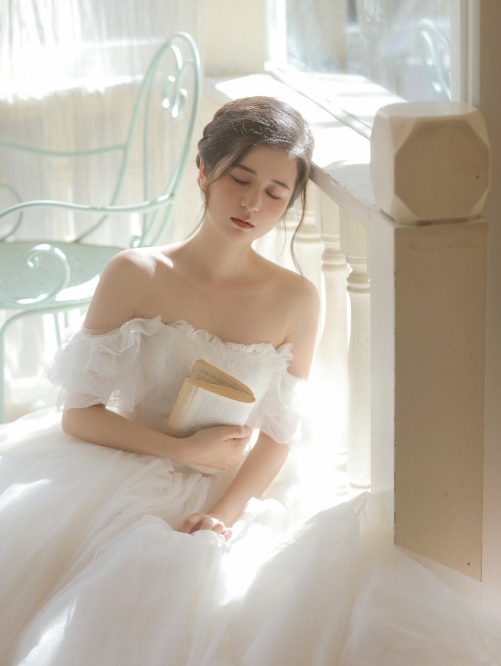 a woman in a white dress holding a book