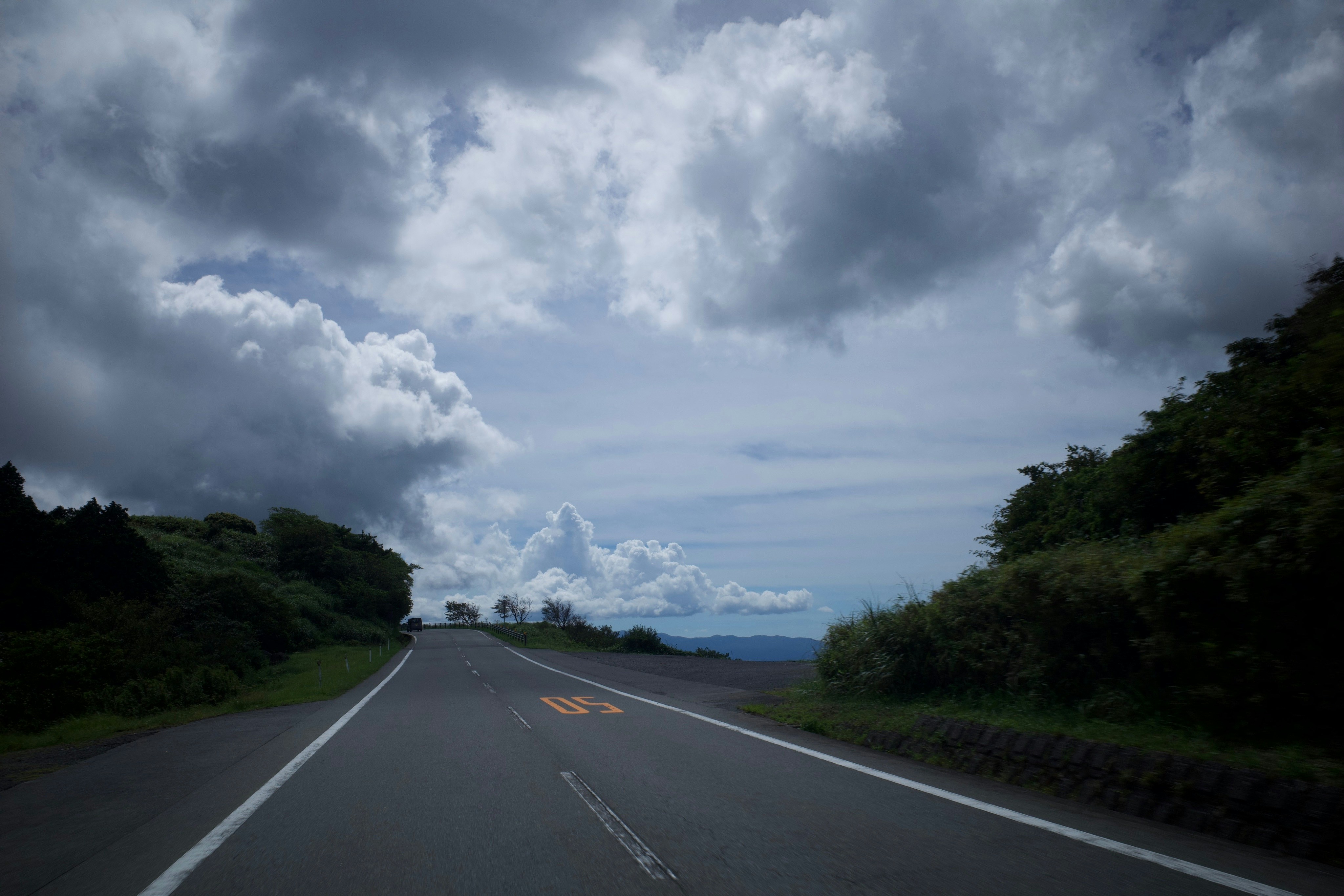 an empty road with a cloudy sky in the background