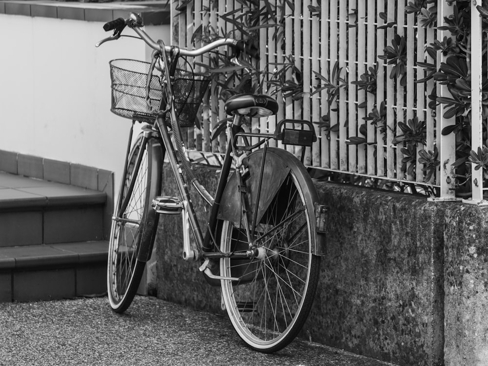 a bicycle parked next to a building with a fence