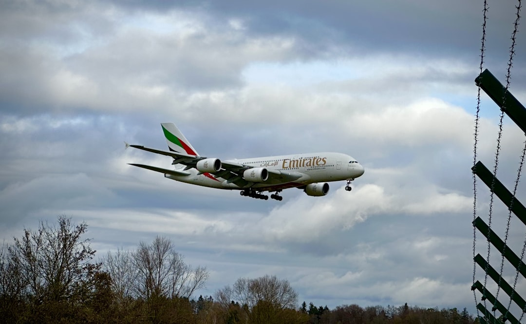 a large jetliner flying through a cloudy sky, Emirates Airbus A380