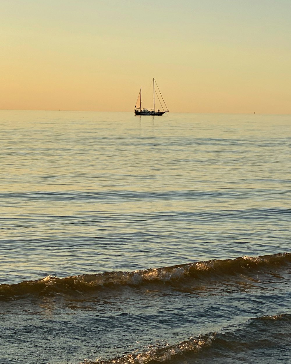 a sailboat is out on the ocean at sunset