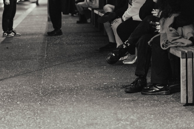 a black and white photo of people sitting on a bench