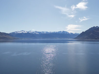 A crisp alpine lake reflecting snow-capped peaks under a clear blue sky.