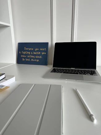 A creative workspace with a laptop, notes, and historical books open, symbolizing thoughtful sponsorship planning.