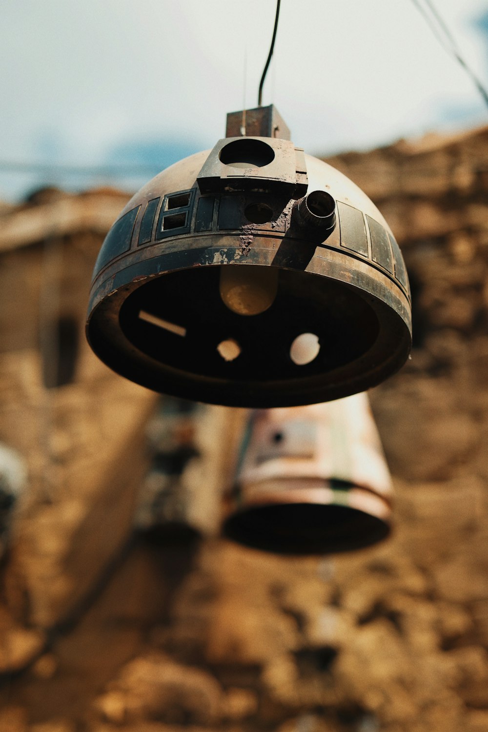 a metal object hanging from a wire next to a building