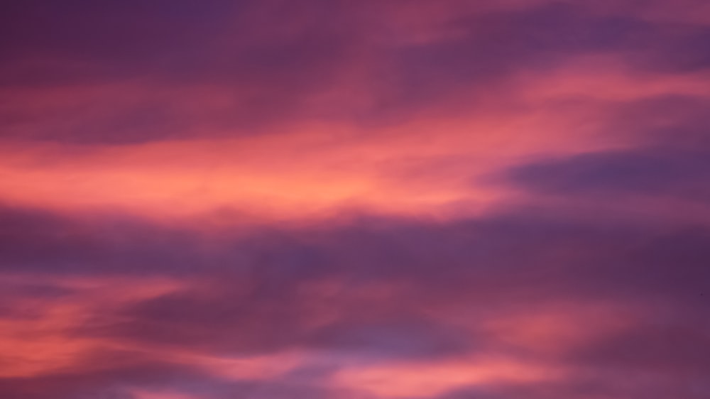 a plane flying in the sky at sunset