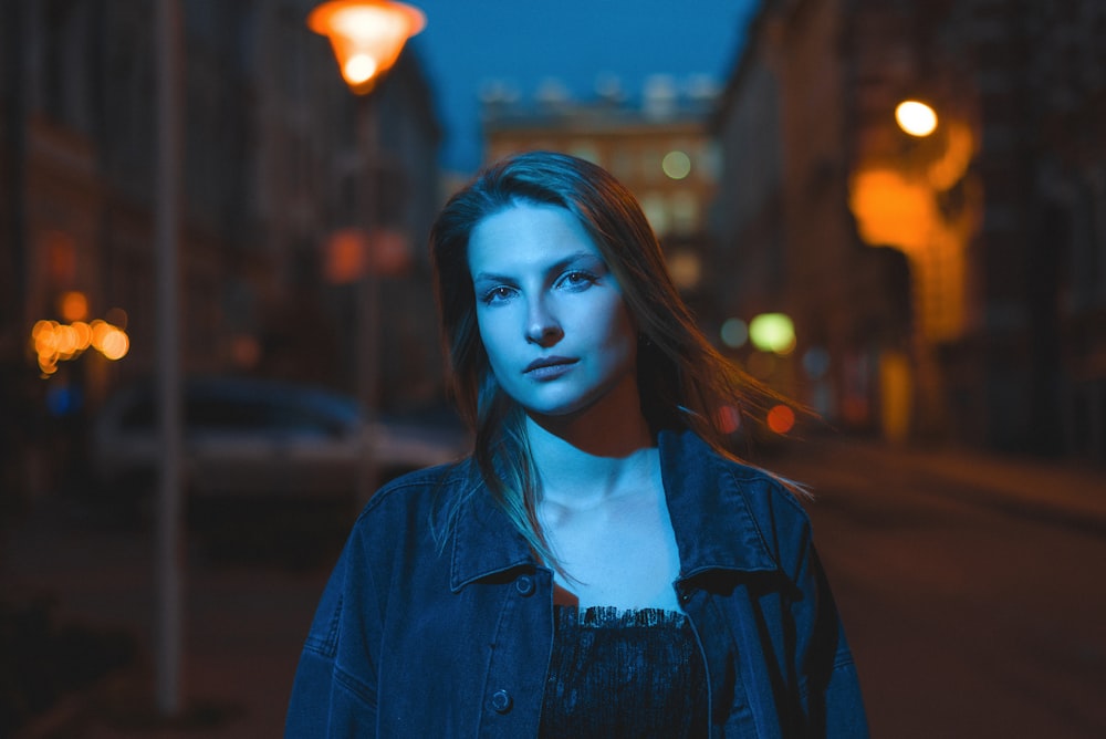 a woman standing on a city street at night