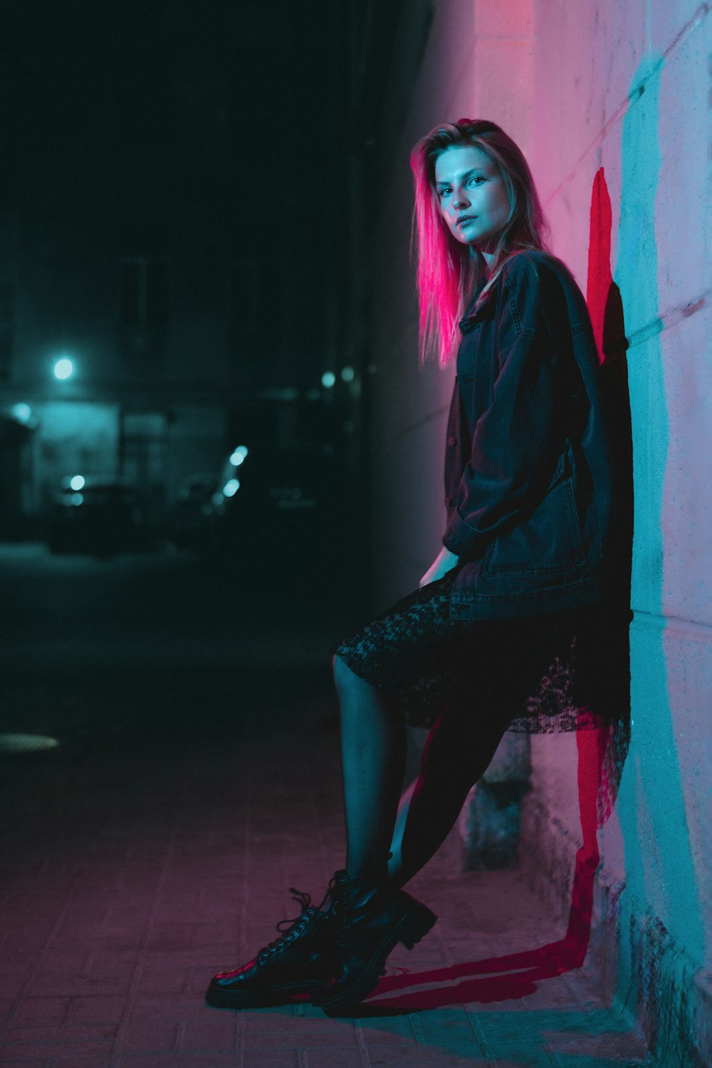 a woman with pink hair sitting on a wall