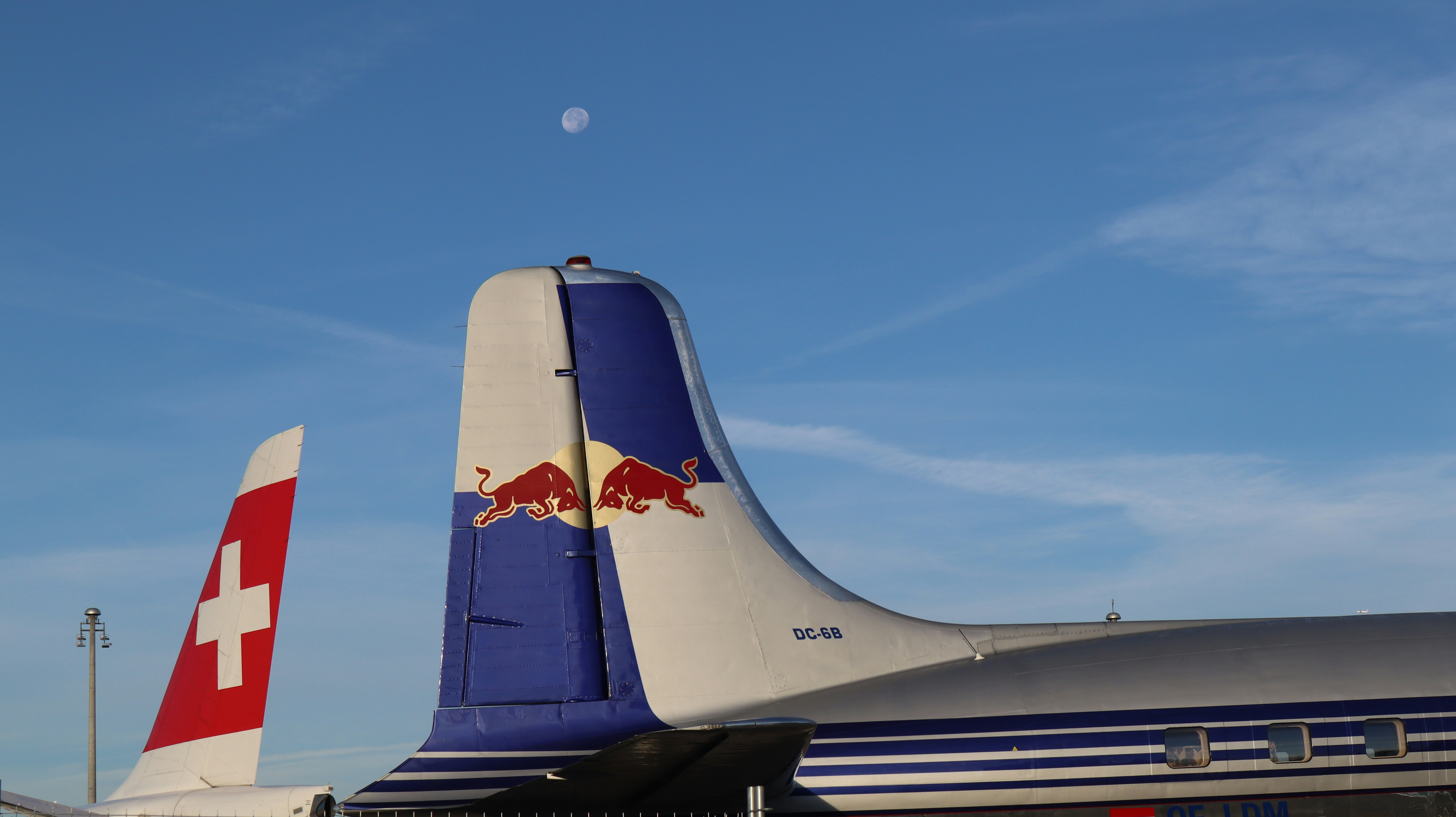 a large jetliner sitting on top of an airport tarmac, Redbull und Swiss Flugzeug mit Vollmond.
