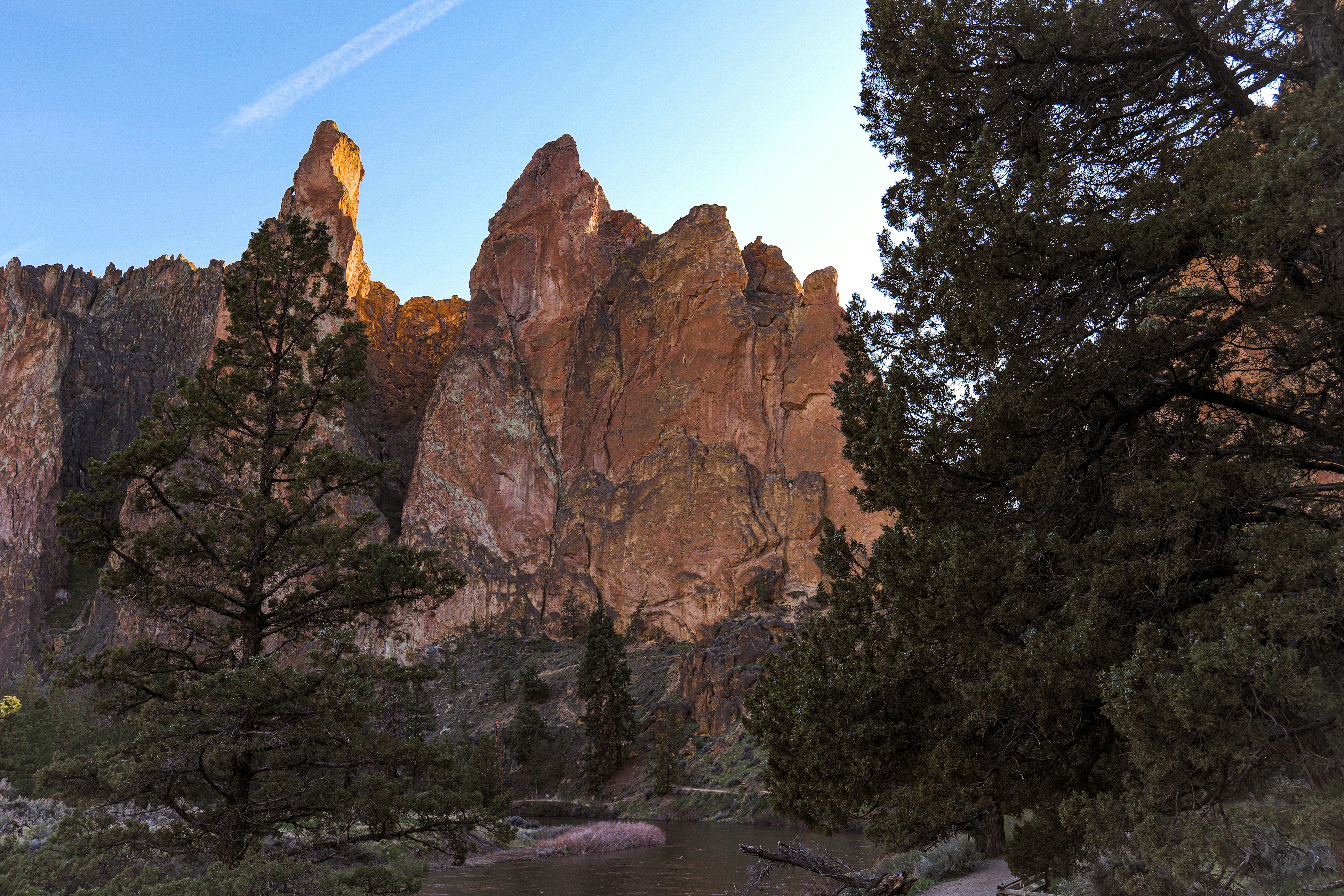 a river surrounded by trees and mountains under a blue sky