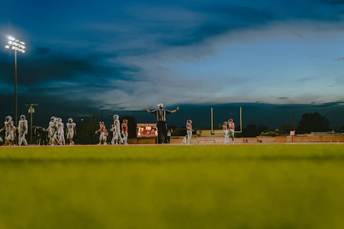 Action shot of a quarterback throwing a football under stadium lights.