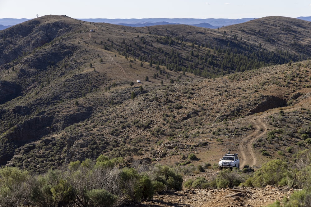 a truck driving down a dirt road in the mountains