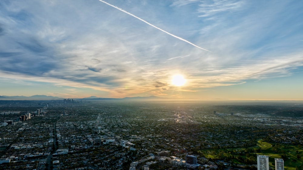 the sun is setting over a city with tall buildings